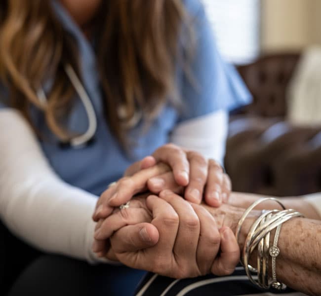 Close up of a nurse holding a patients hands
