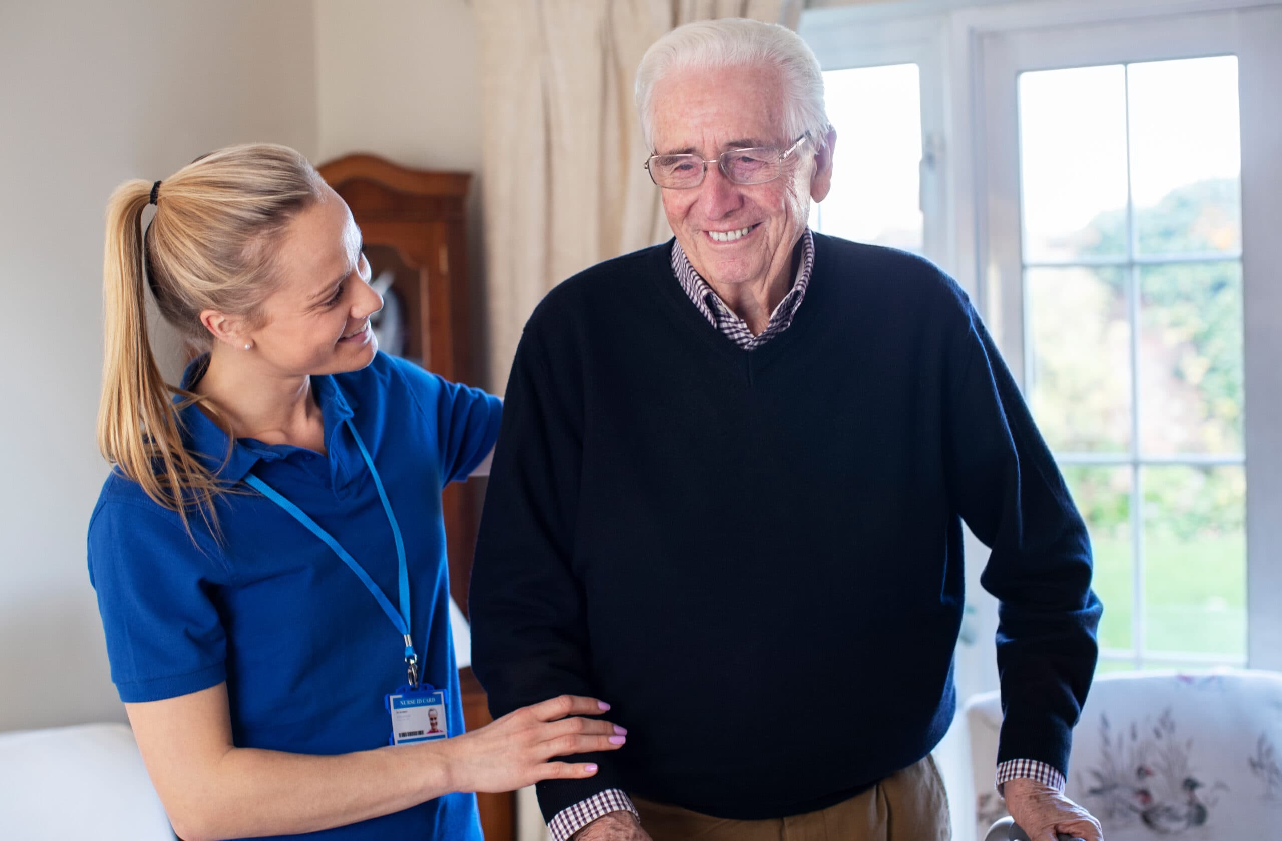 Senior Man Using Walking Frame With Care Worker