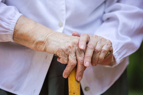 senior-womans-hands-holding-walking-stick-P7BC3D9