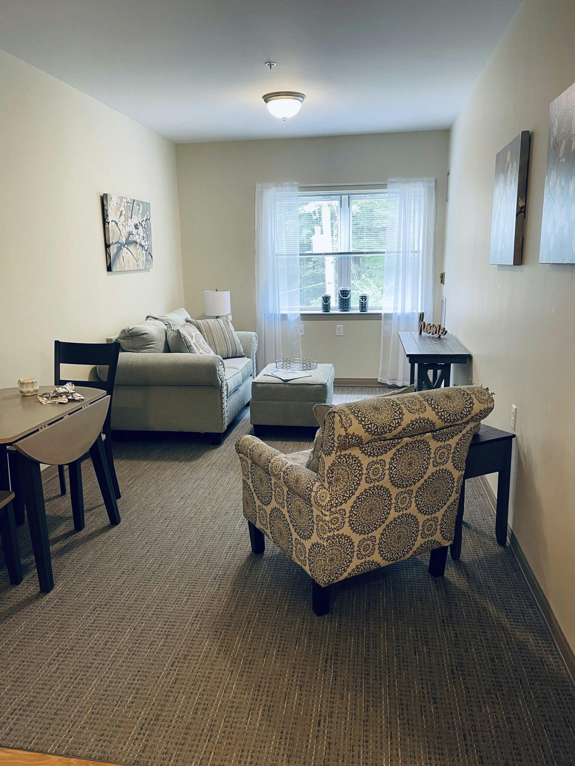 A living room in an assisted living facility with a dining table and chairs.