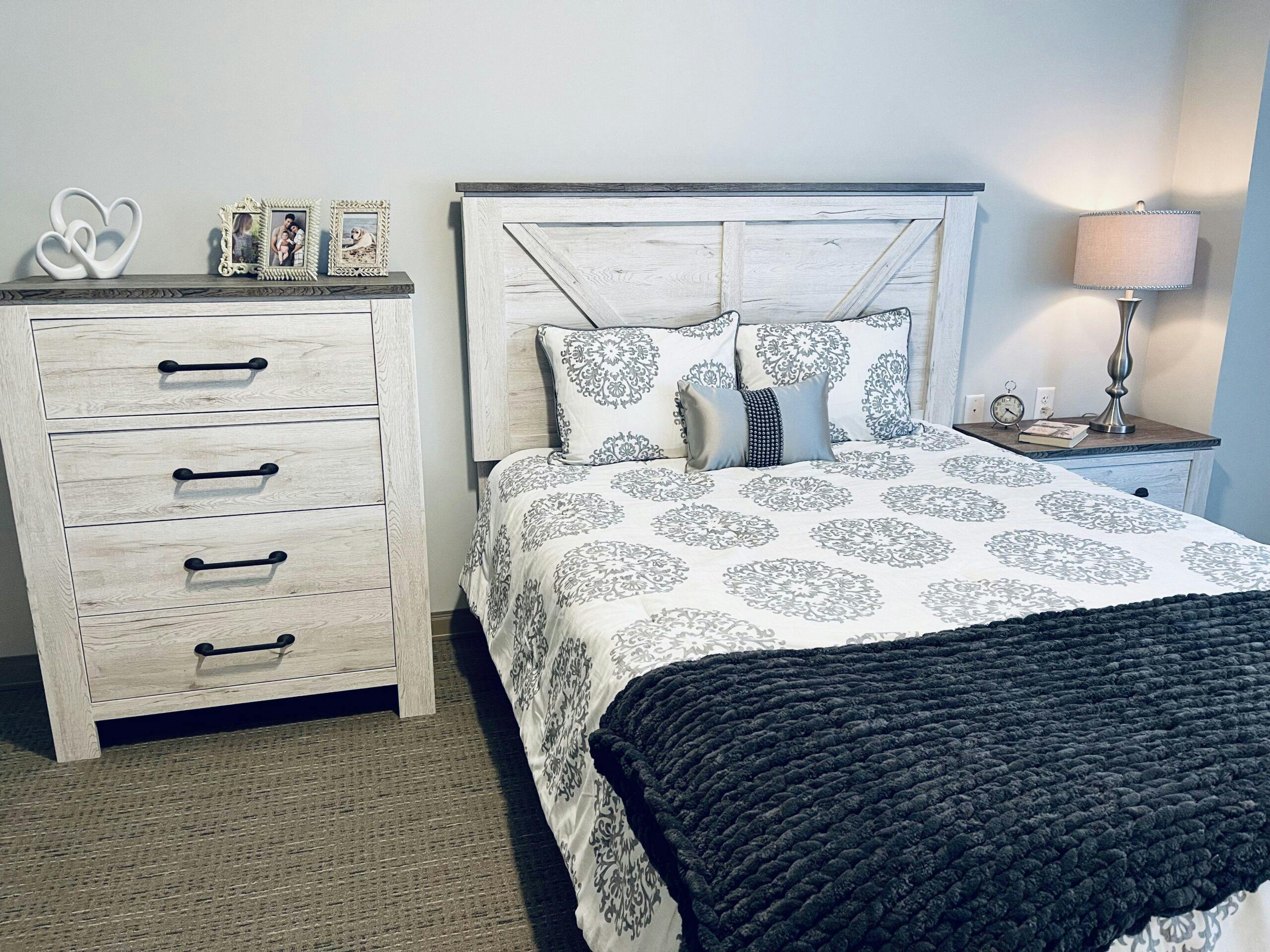 An assisted living bedroom with a bed and dresser.